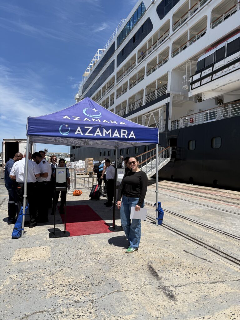 An image of Kathryn, owner of Mistral Winds Travel, standing at the Azamara tent preparing to board the Azamara South Africa Cruise. 
