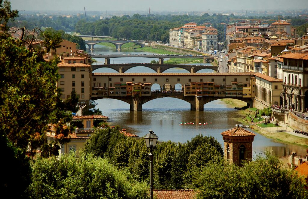 Ponte Vecchio bridge over Arno River in Florence Italy with terracotta rooftops and Tuscan hills - iconic Renaissance architecture and historic landmarks for luxury Italy travel and cultural tours in Tuscany