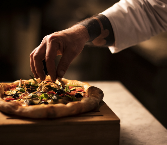 Italian chef preparing artisan pizza for wine pairing at Tuscan restaurant culinary experience