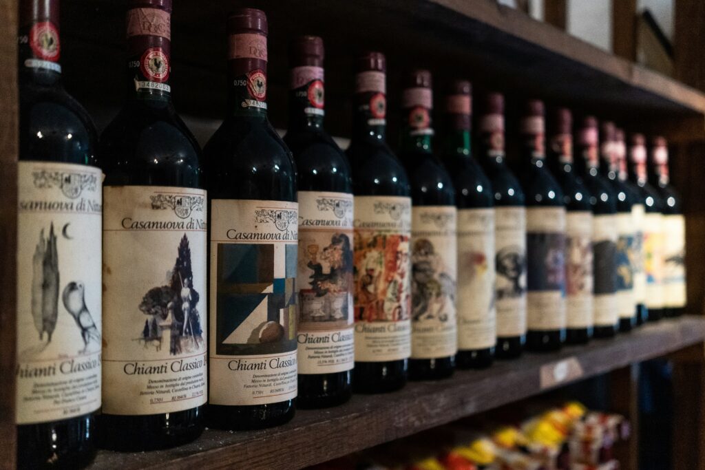 Your guide to Tuscany's Nobile Wines: Chianti Classico DOCG wine bottles with Black Rooster seal aging on cellar shelf in Tuscany Italy