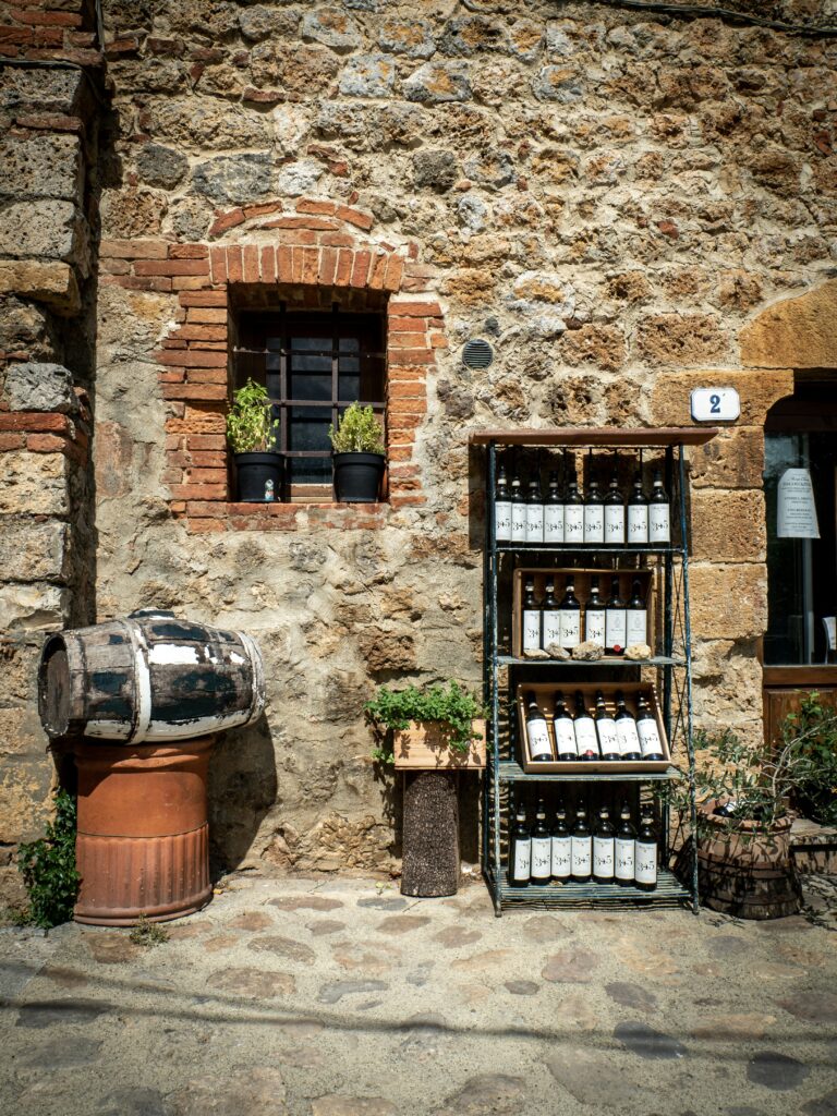 Guide to Tuscany's Nobile Wines: Traditional Tuscan wine shop storefront with vintage wine barrels and bottles on rustic stone wall