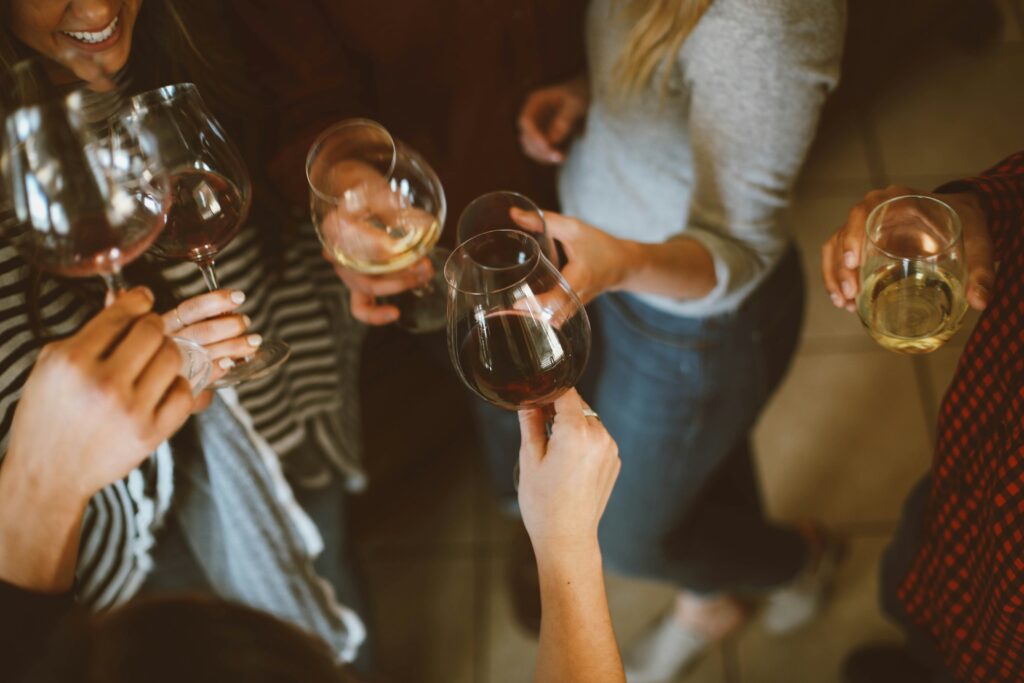 Friends toasting with red and white wine glasses at gathering - Thanksgiving wine pairing celebration with diverse wine selections