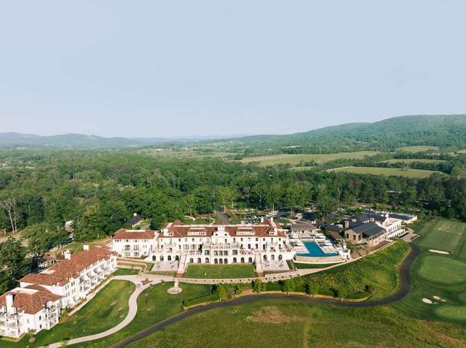 Aerial view of Keswick Hall Forbes Five-Star luxury resort with Italianate architecture, infinity pool, and Blue Ridge Mountains in Charlottesville Virginia wine country