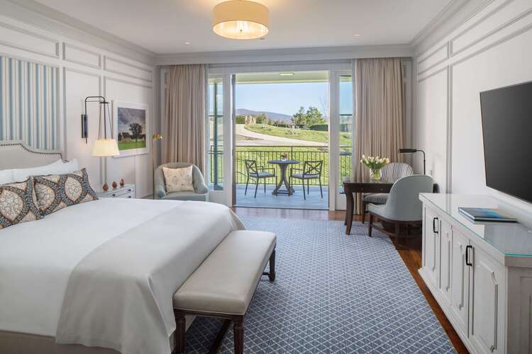 Elegant guest room with king bed, Blue Ridge Mountain views, and private balcony at luxury Charlottesville Virginia resort