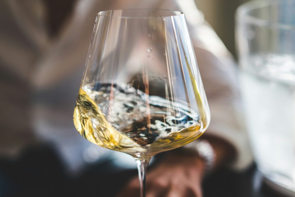 White wine swirling in glass showing proper tasting technique - Chardonnay and Riesling pairing tips for Thanksgiving dinner