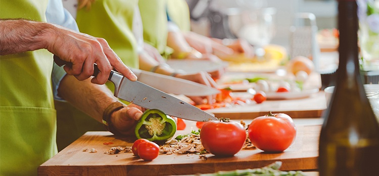 Hands preparing fresh vegetables during a European cooking class as part of a culinary travel experience