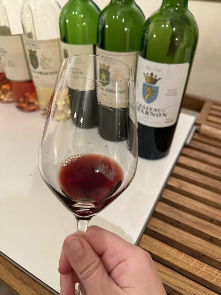 Wine tasting in the Bandol AOP in Provence featuring a glass of red Bandol wine with bottles from the region in the background